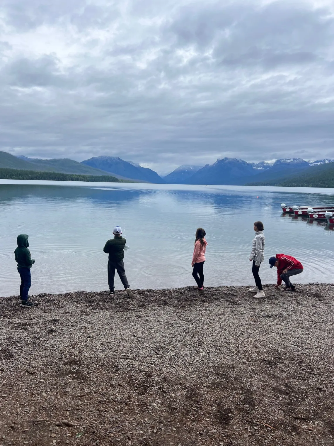 best-places-to-stay-in-glacier-national-park-8 Children on the Lake McDonald shoreline looking out over a calm lake, which is one of the best things to do in Glacier National Park