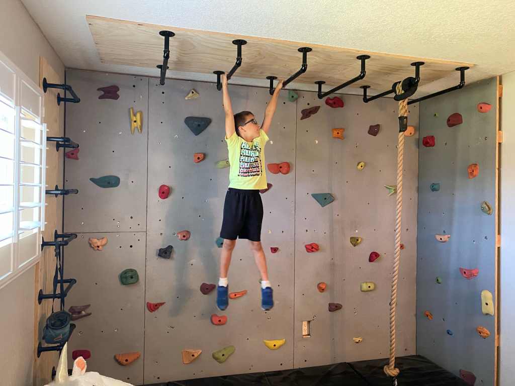 A kid hanging on the monkey bars indoor