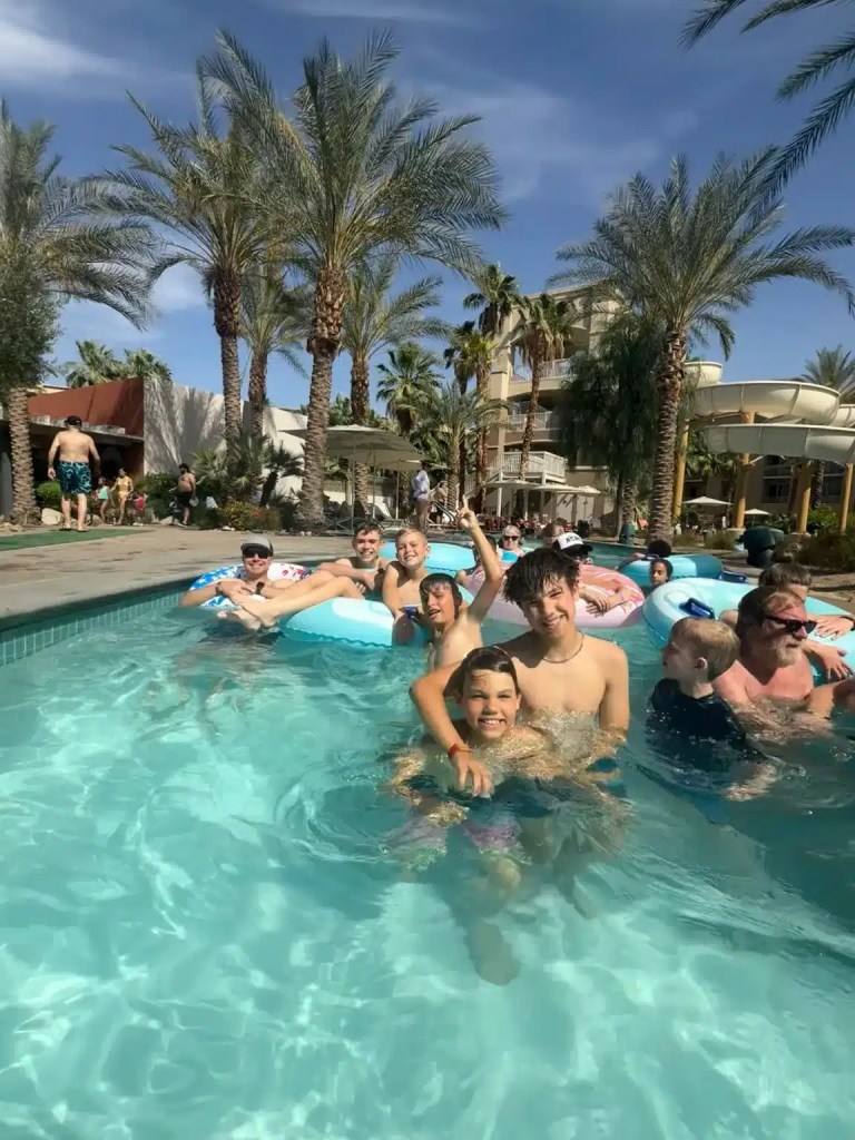 Kids floating in an innertube with waterslides and palm trees behind them. They are in Palm Desert, one of the best travel destinations in January.