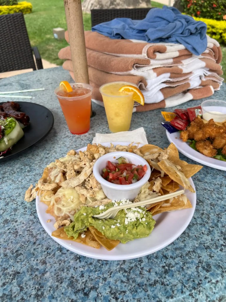 A plate of nachos with two tropical drinks show all-inclusive dining in one of the best vacation cities in Mexico