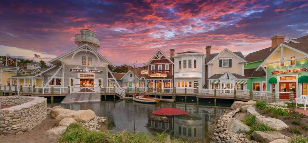 Charming waterfront shops and buildings in Cape Cod at sunset, with colorful seaside architecture along a calm waterway.