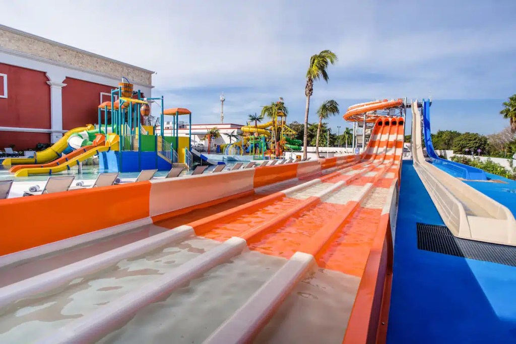 Colorful water slides at a water park with various attractions, including a play area and multiple slide options for families.