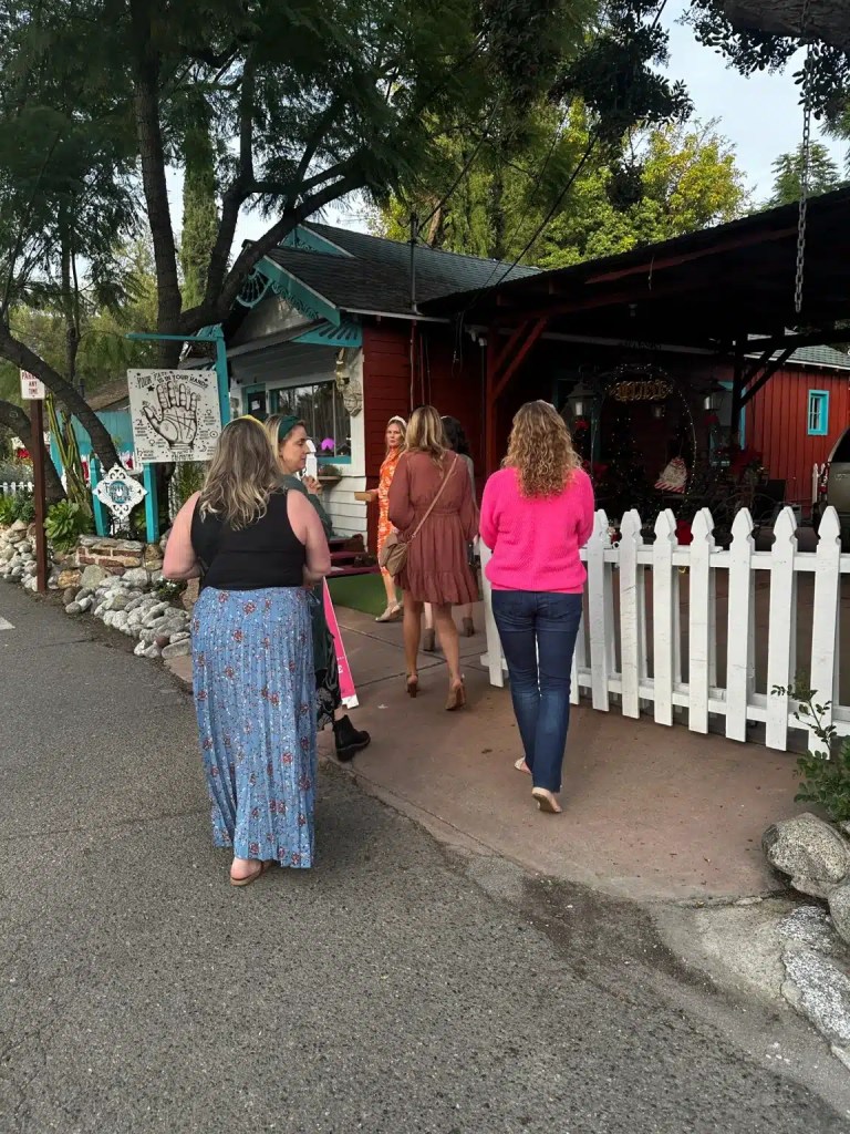 A group of women walking toward a colorful building, surrounded by greenery and decorative elements while enjoying cute things to do in San Juan Capistrano.