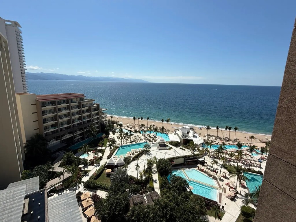 img_2311 High-angle view of the Dreams Vallarta Bay beachfront resort in Puerto Vallarta with multiple swimming pools, palm trees, and the ocean.