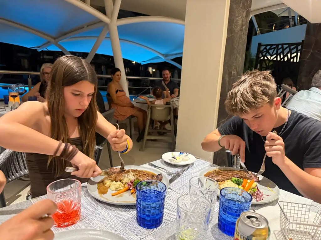 Two teens cutting their steak dinners at a restaurant at the Dreams Vallarta Bay resort.