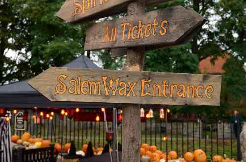 A wooden signpost with arrows pointing to 'Spirit Market', 'All Tickets', and 'Salem Wax Entrance' during the Haunted Happenings in Salem Ma in Oct.