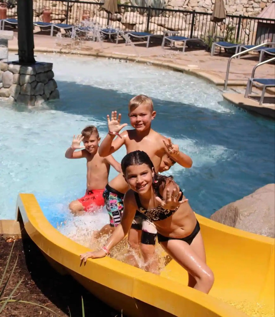 Three kids posing on a waterslide at a resort