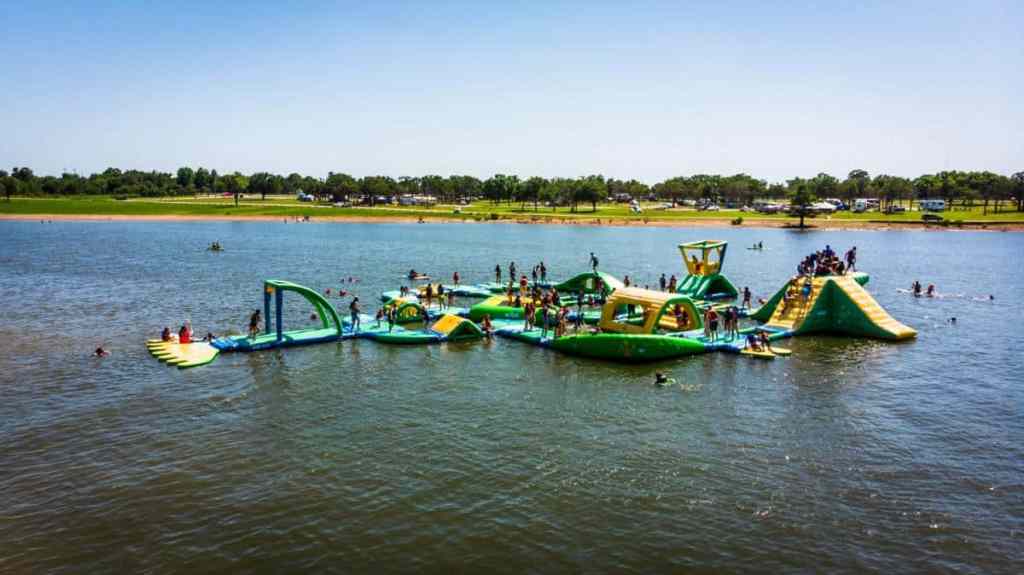 A campground with an inflatable water park on the lake
