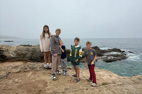 Five children posing on a rocky cliff in Malibu, California overlooking the ocean on a foggy day