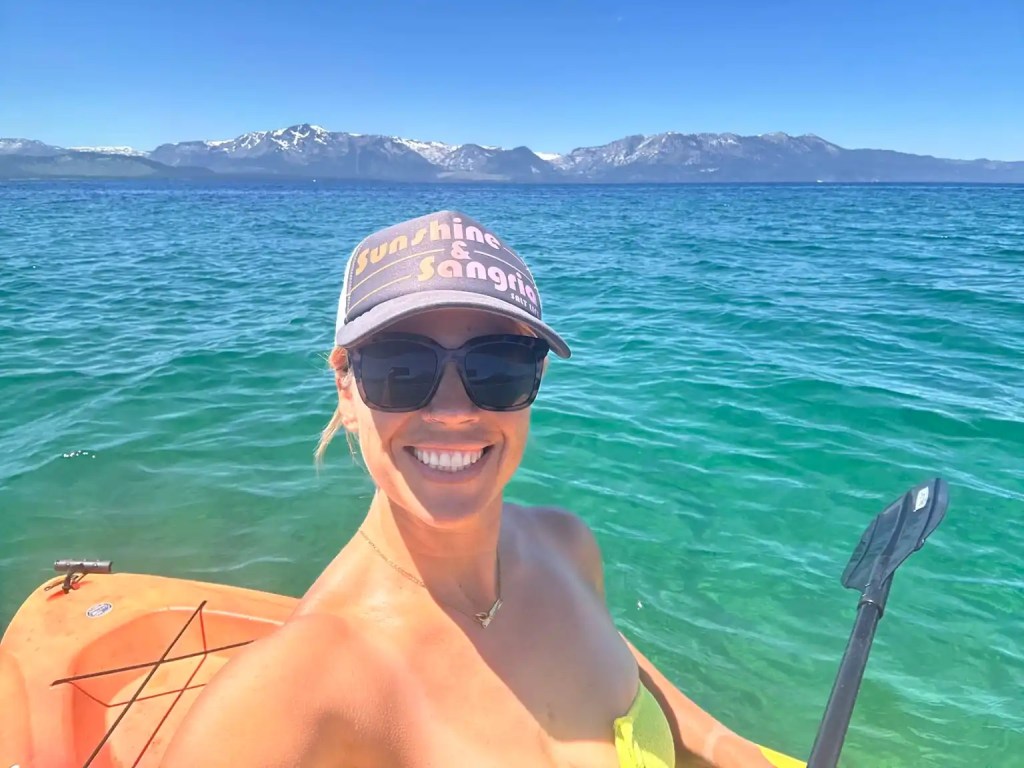 A smiling woman kayaking in the turquoise waters of Lake Tahoe
