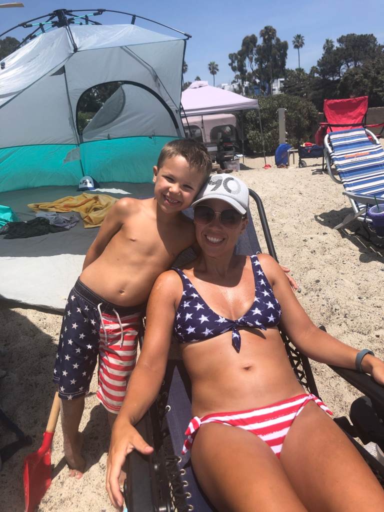 A woman and young boy smiling with tents behind them at the Doheny State Beach campground