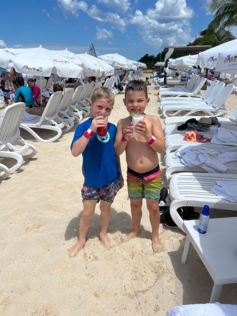 Two kids sipping drinks while on an affordable family vacation in Mexico