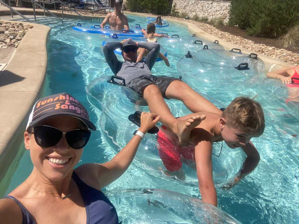 Three people smiling as they float in a lazy river in Texas