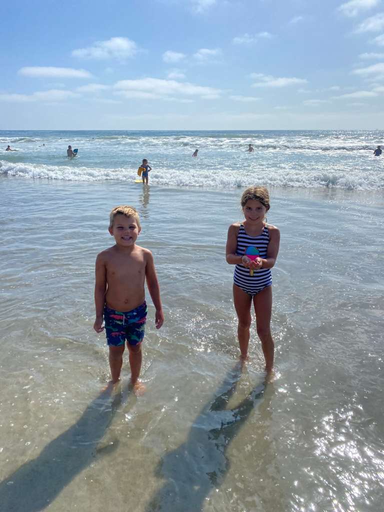 Two kids smiling in the ocean at one of the best beaches of San Diego