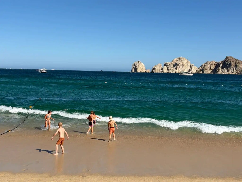 Kids playing in the waves on a Cabo family vacation