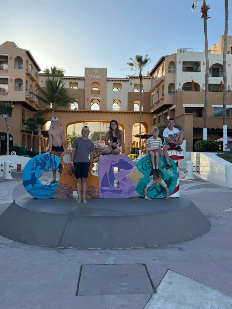 Kids posing with a colorful Cabo sign on a Cabo family vacation