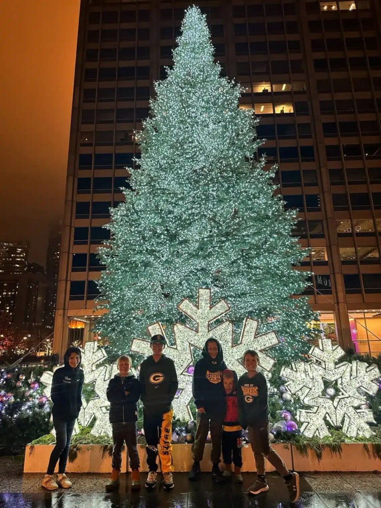 Six kids posing with a Christmas tree in one of the great places to go for Christmas
