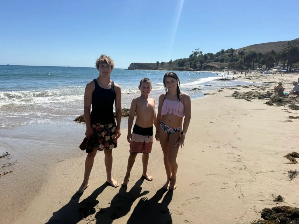 Three kids posing on the beach while beach camping at Refugio State Beach