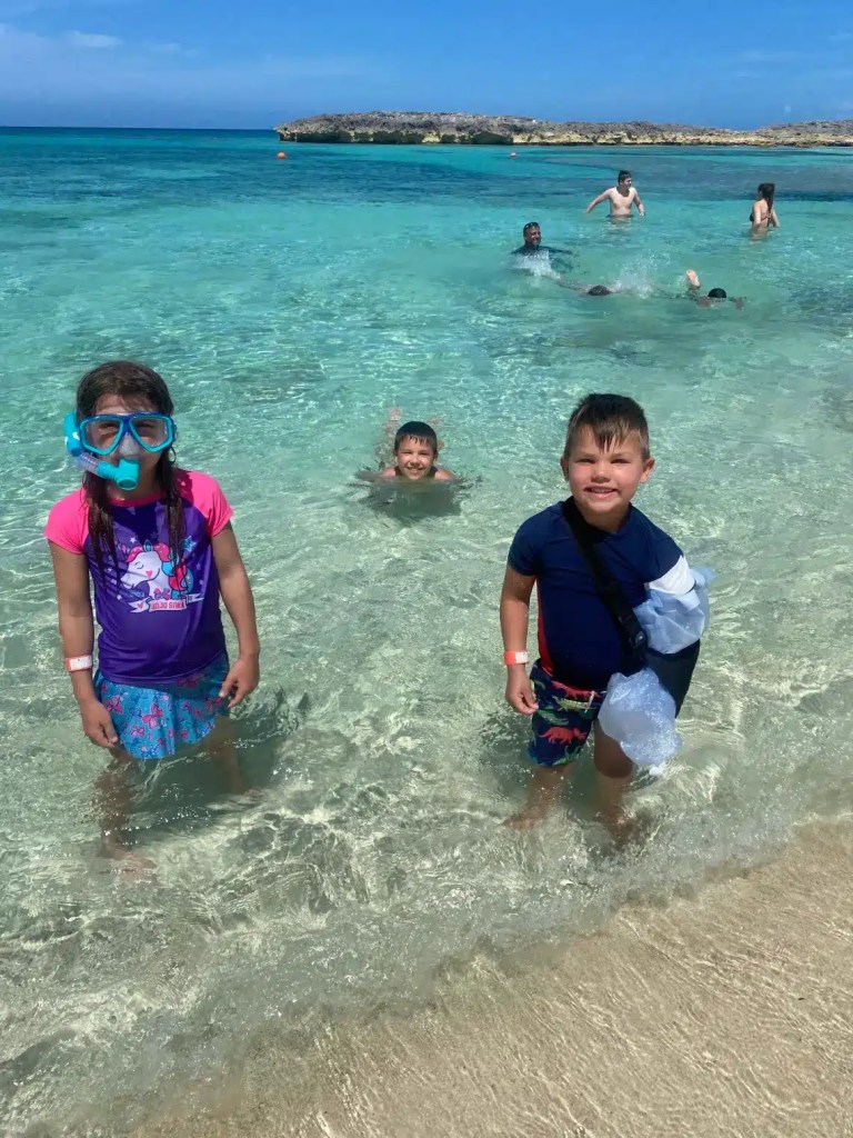 Three smiling kids in crystal-clear water one of the best Bahamas Islands for families