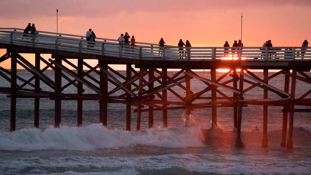 A picture of a pier on a beach with a beautiful sunset at one of the best October getaway destinations