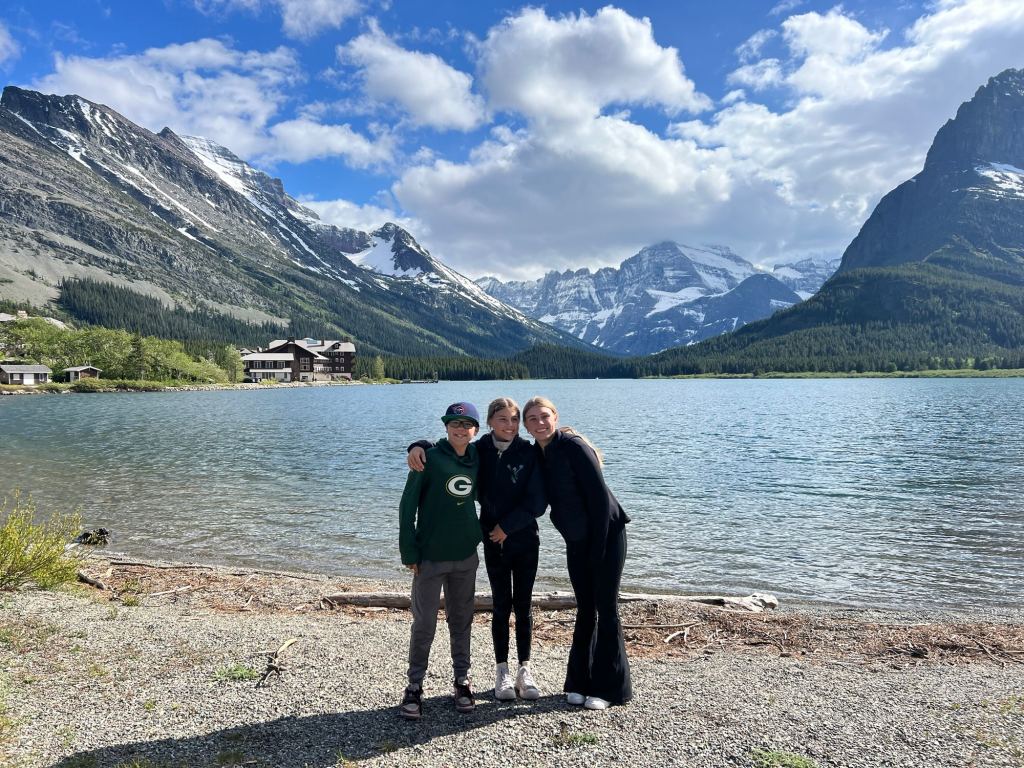 Teens posing in front of a lake with mountains in the background on a summer vacation trip