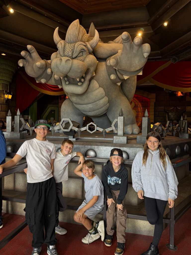 Five kids posing with Bowser at one of the greatest amusement parks in the world