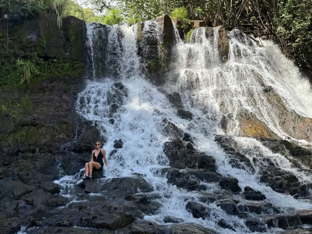 A woman posing with one of the beautiful waterfalls in Kauai, Hawaii