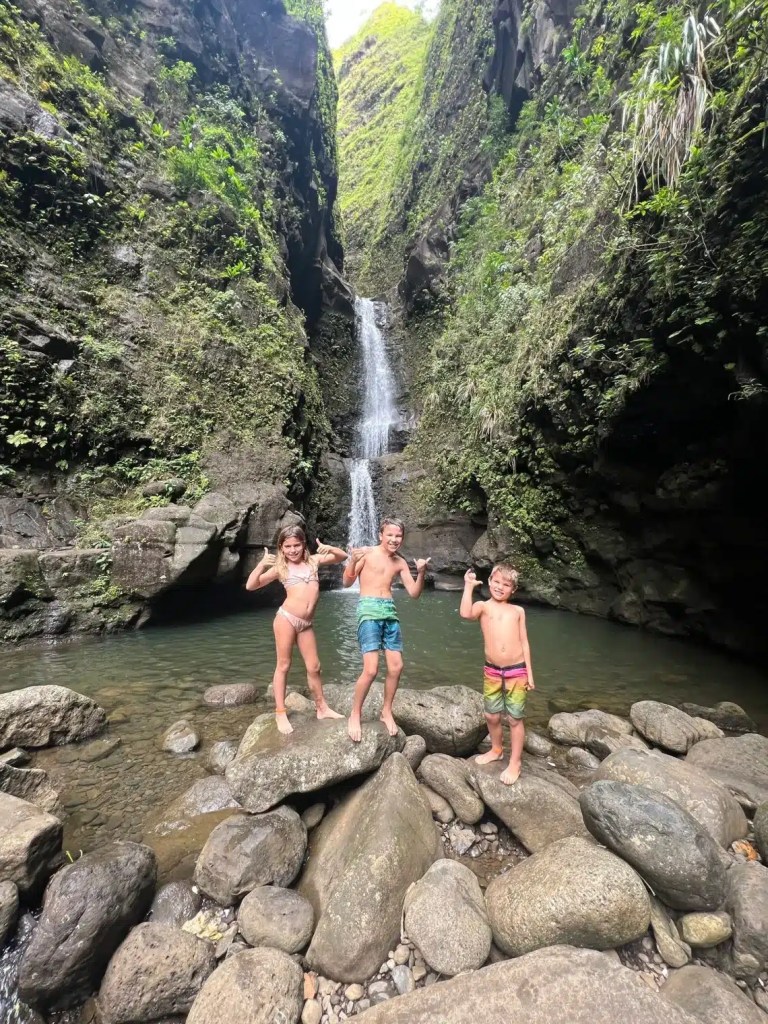 Three kids posing in front of the Makaleha waterfall in Kauai, Hawaii