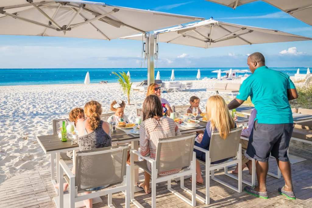 A family eating a meal right near the sand at one of the best family beach resorts