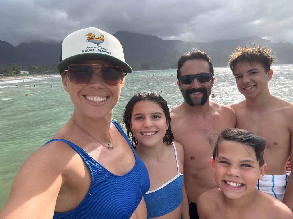 A smiling family smiling with the beach behind them while staying at one of the best beach resorts for families